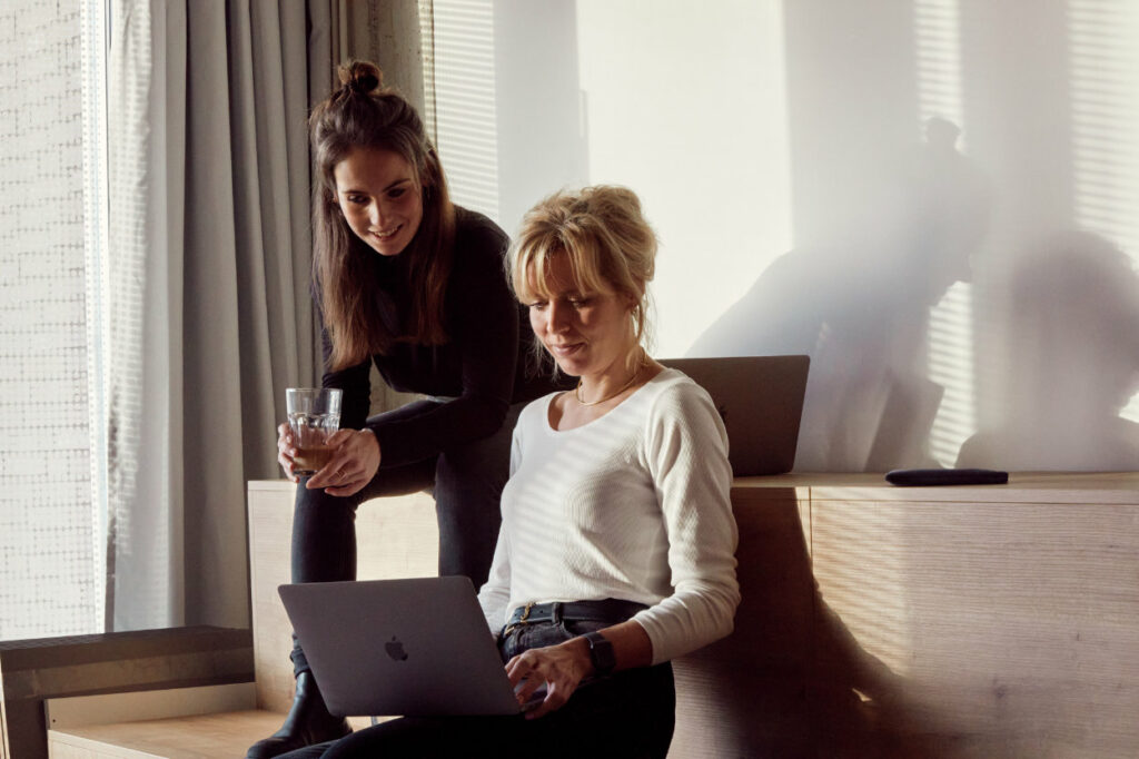 Arbeitssituation zwei junge Frauen im Gespräch vor Laptop