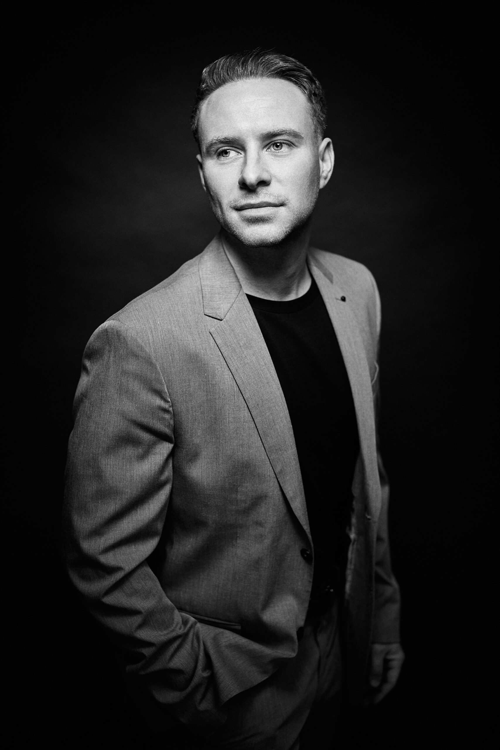 Schwarz-Weiß Portrait Mann im Anzug vor schwarzer Wand
