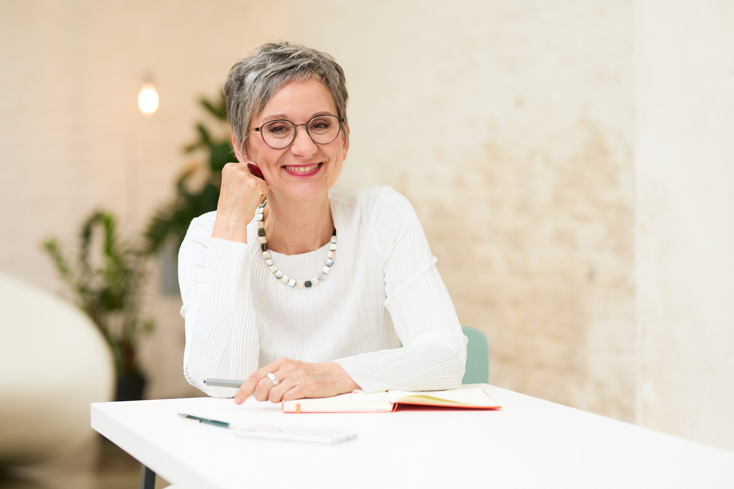 Personal-Branding-Shooting Eva Kräling – am Tisch mit Notizbuch in lockerer Café-Atmosphäre