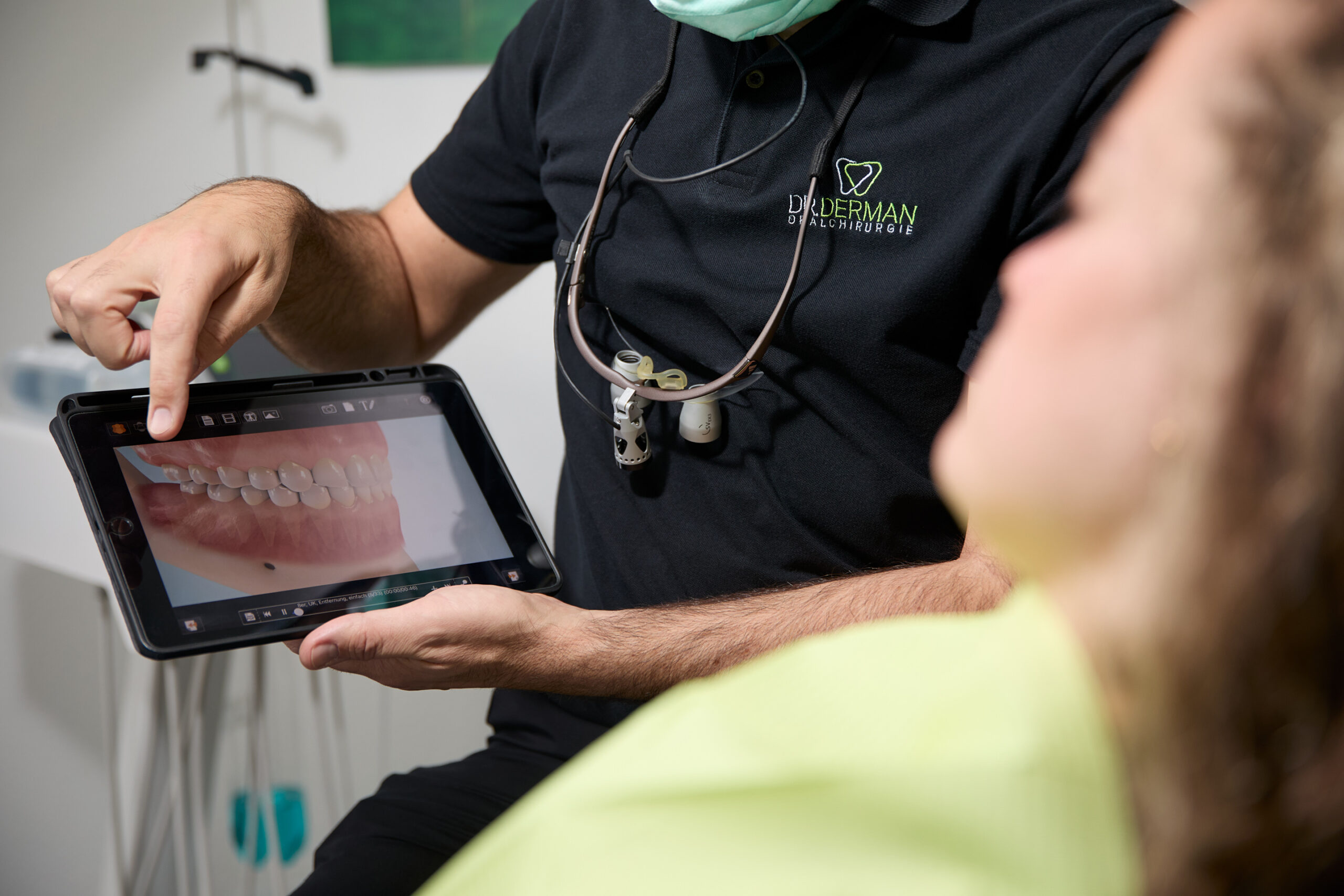 Oralchirurgie Dr. Derman – Zahnarzt erläutert Patientin den Befund anhand eines Tablets