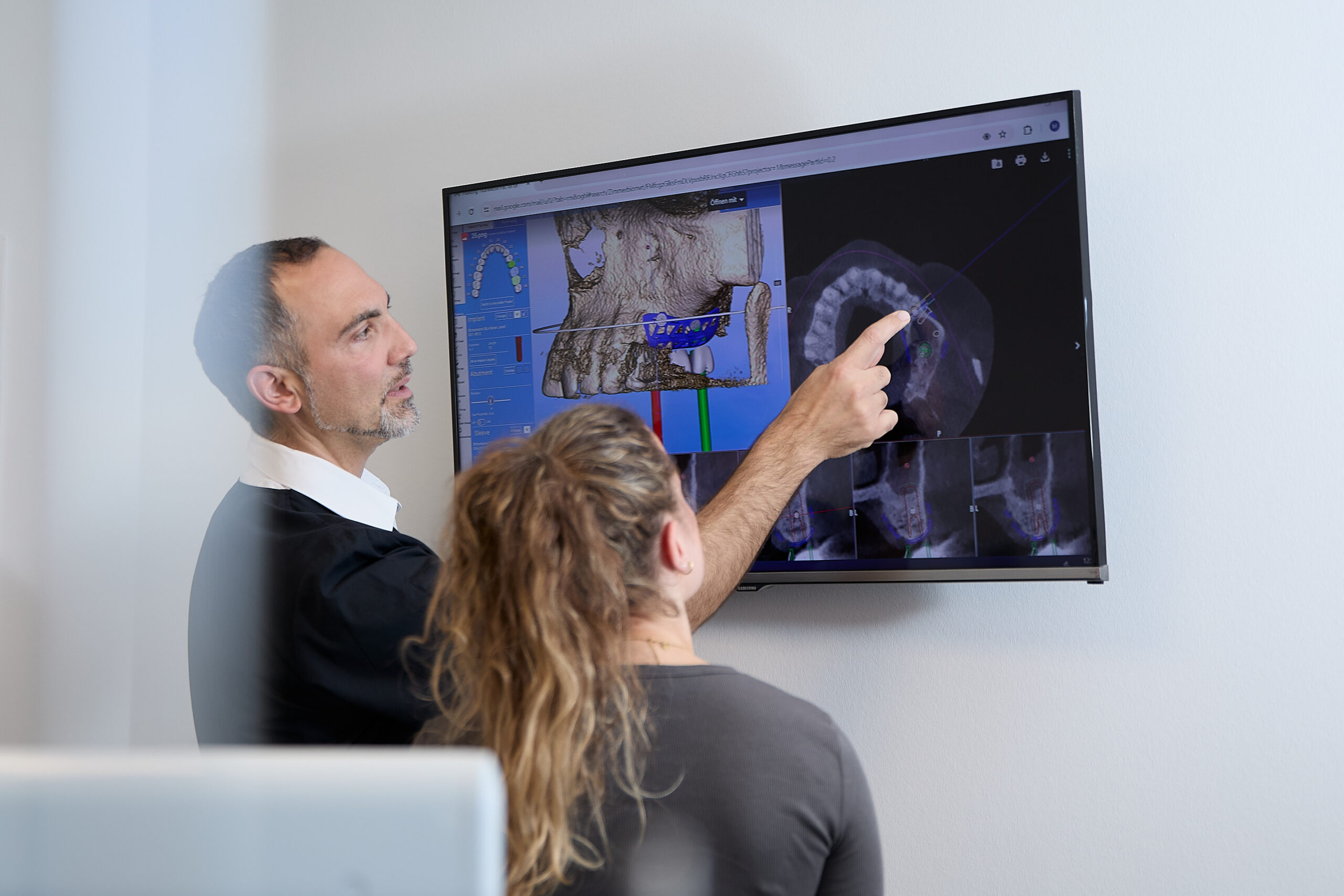 Oralchirurgie Dr. Derman – Besprechung eines digitalen Zahnscans am Wandmonitor